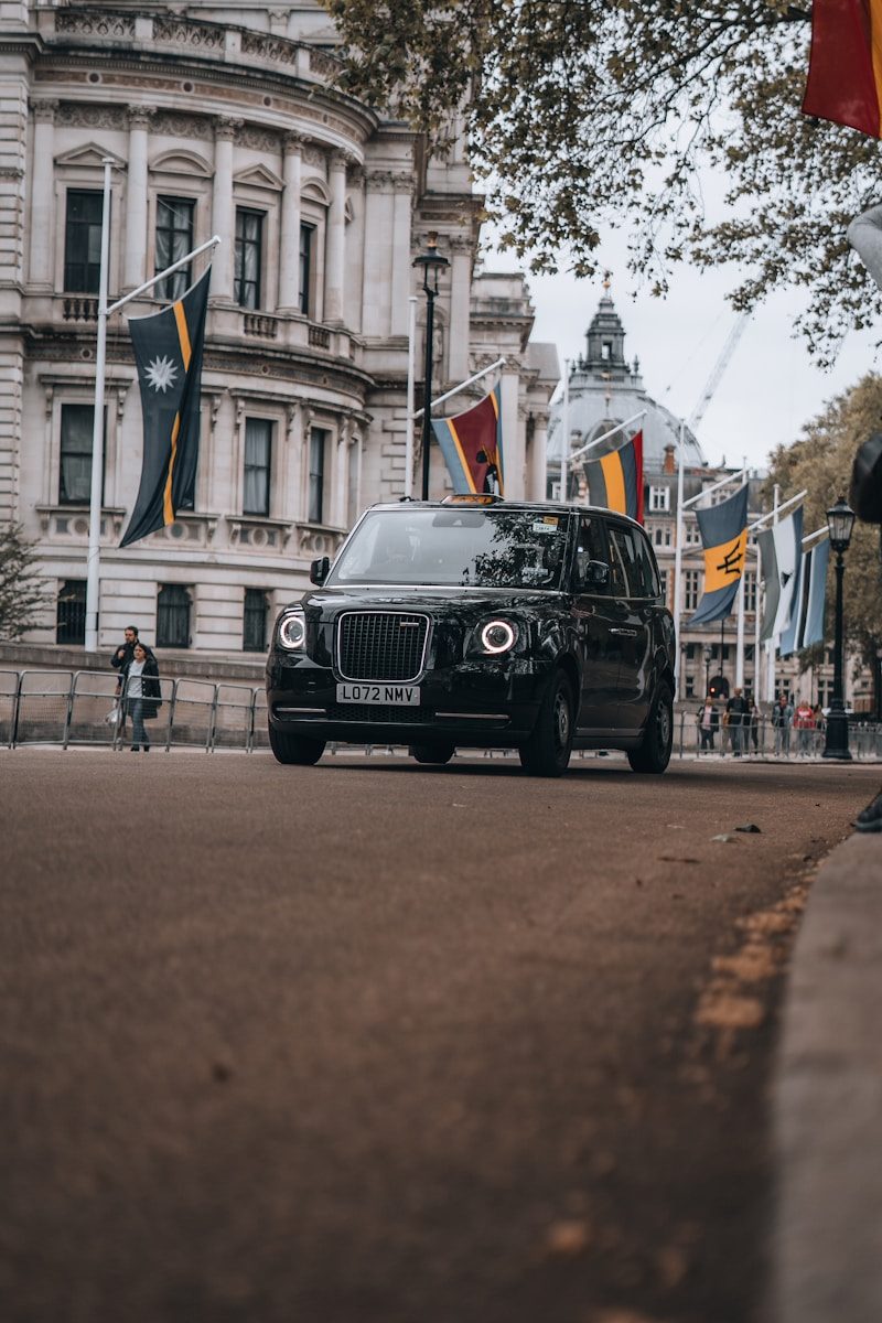 a black car driving down a street next to a tall building